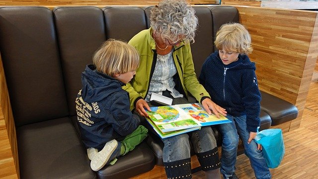 babička prohlíží knížku s vnoučaty